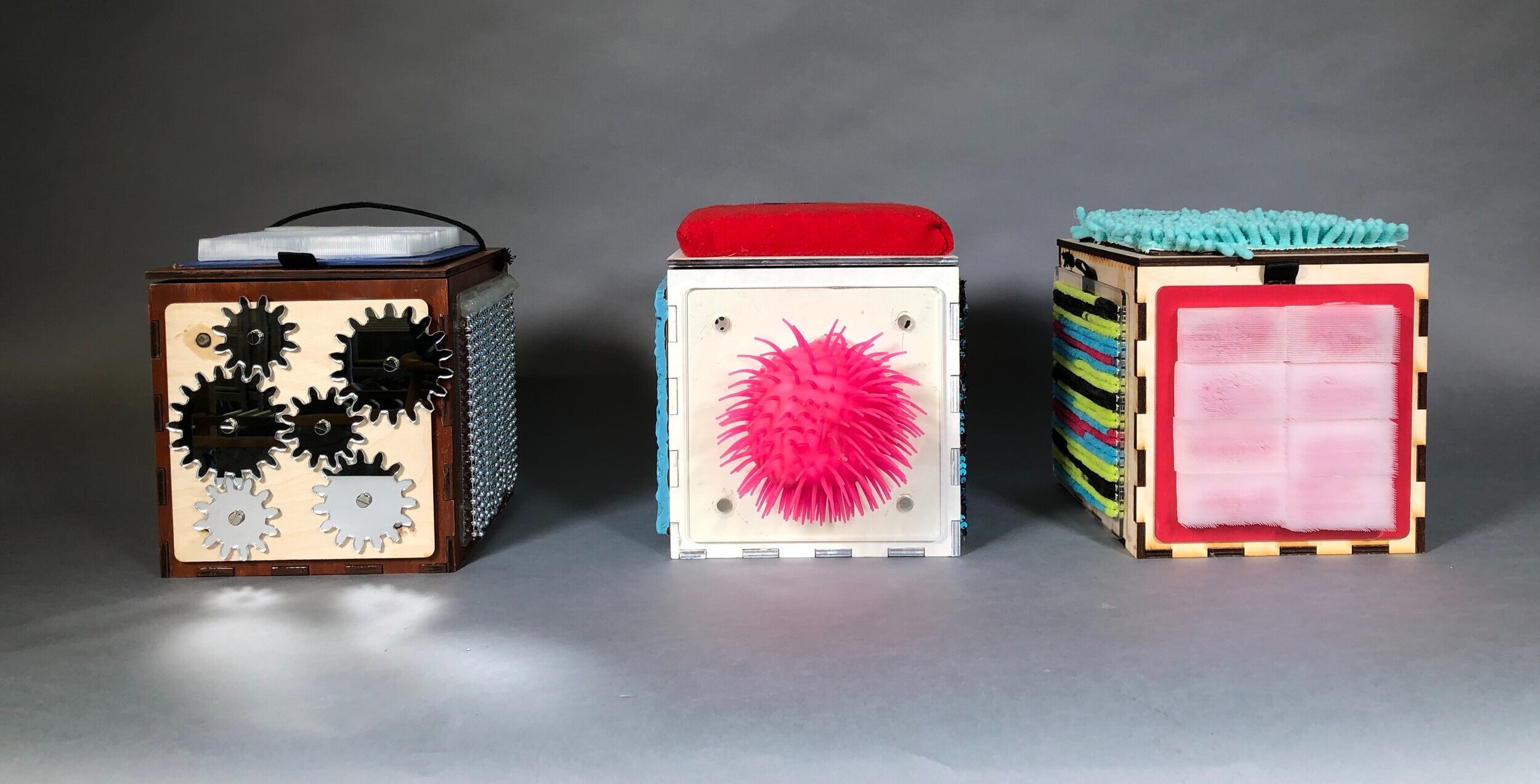 Three TactTiles Cube sensory engagement systems, with mirrored gears, sensory brushes, and a silicone urchin.